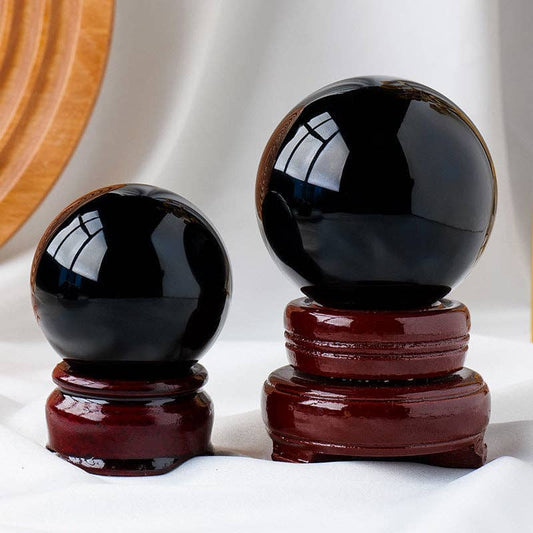 Black Obsidian Sphere set on wooden stands, showcasing their polished finish and unique properties