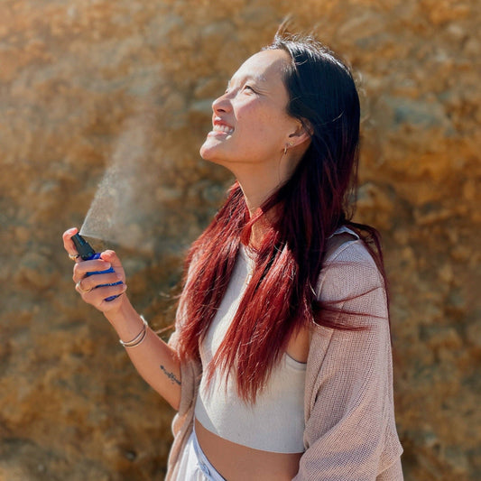 Woman using Blue Lily Healing Aromatherapy Spray outdoors with a joyful expression
