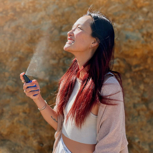 Woman using Blue Lily Healing Aromatherapy Spray outdoors with a joyful expression
