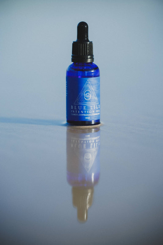Blue Lotus Intention Oil in a blue glass dropper bottle reflecting on a smooth surface