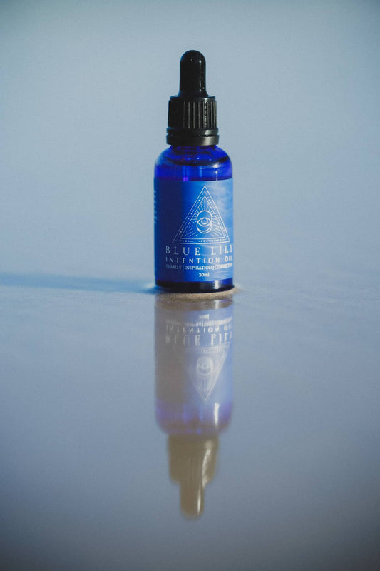 Blue Lotus Intention Oil in a blue glass dropper bottle reflecting on a smooth surface