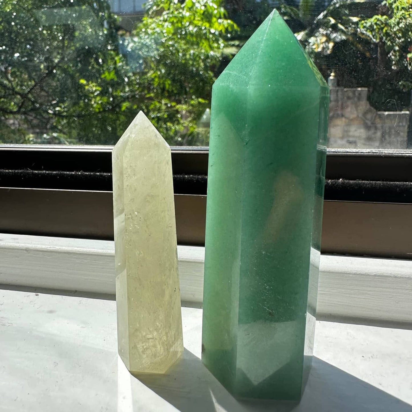 Natural Green Aventurine Tower next to a smaller crystal tower on a sunny windowsill