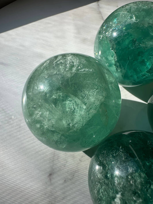 Natural Green Fluorite Sphere showcasing vibrant green hues and translucent surface for decor or healing