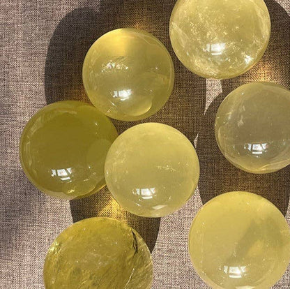 Genuine Natural Citrine Crystal Sphere set displaying various sizes and translucent colors on a textured surface