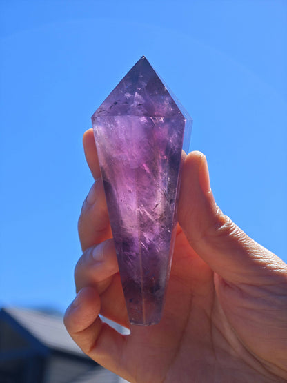 Natural Brazilian Amethyst Wand held in hand, showcasing its beautiful purple hues and crystal clarity