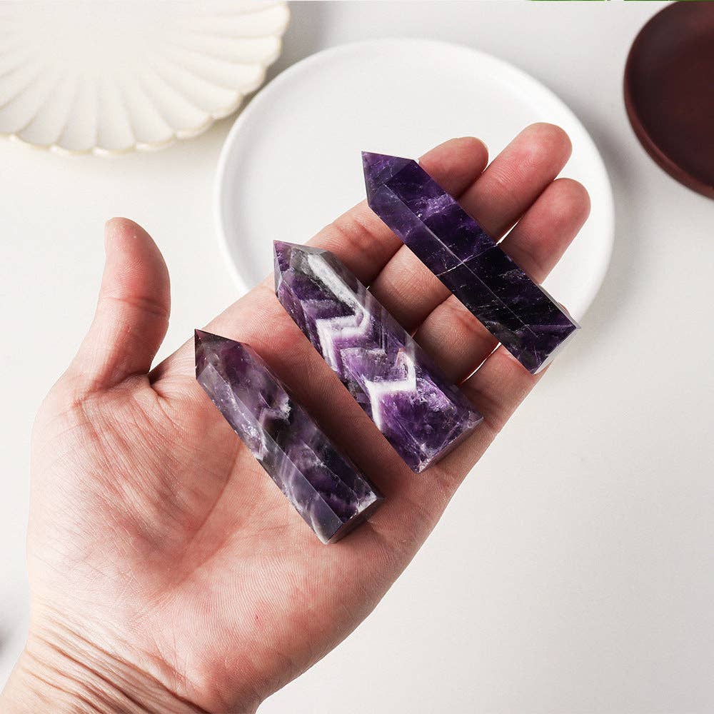 Natural Dream Amethyst Tower crystal in hand showcasing unique patterns and vibrant purple hues