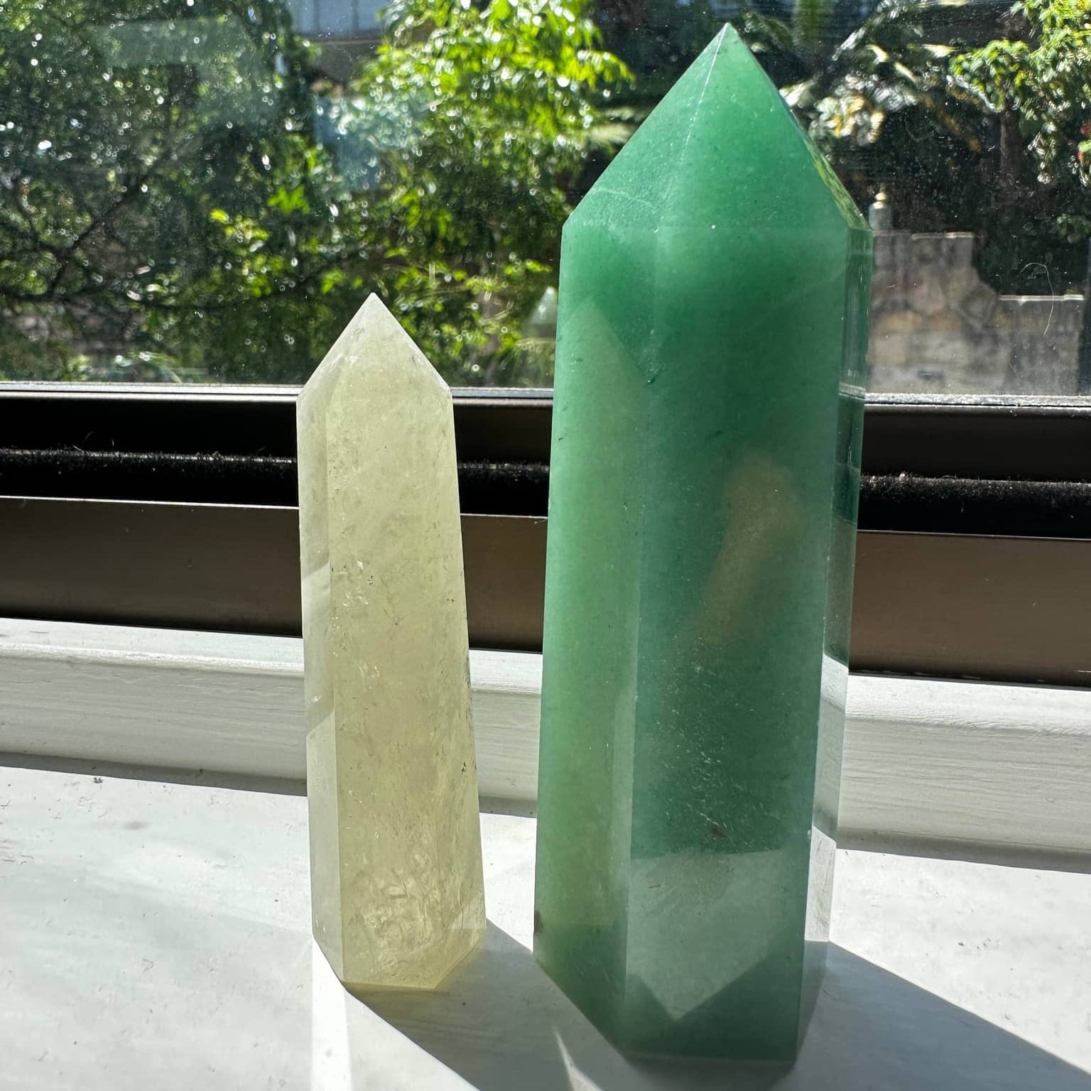 Natural Green Aventurine Tower next to a smaller crystal tower on a sunny windowsill
