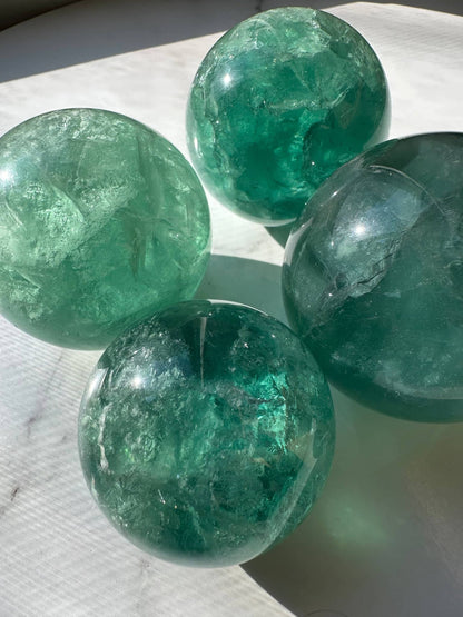 Natural Green Fluorite Sphere set showcasing vibrant green colors with clear transparency and unique textures