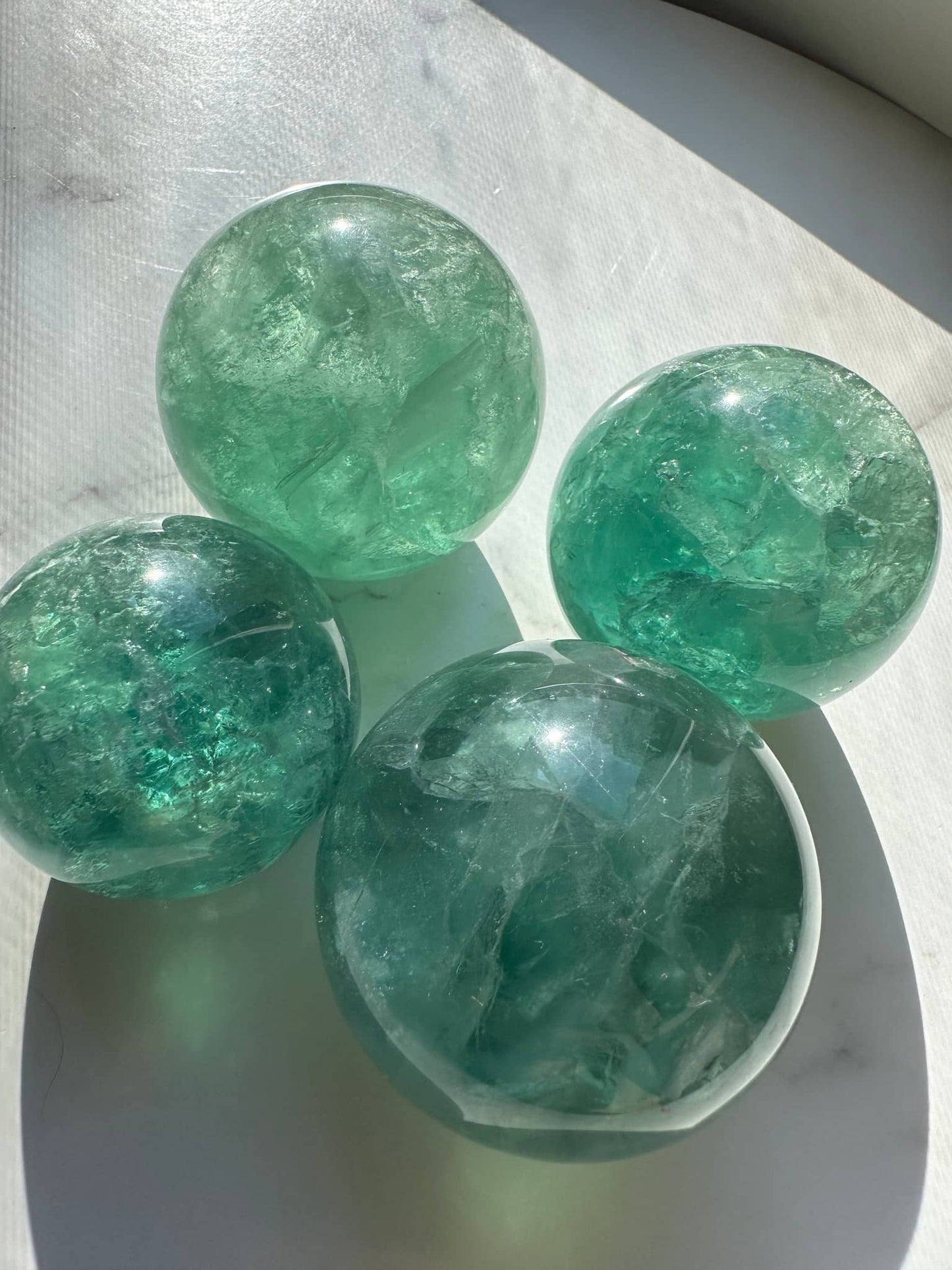 Natural Green Fluorite Sphere set of four with sparkling translucent surfaces and unique swirling patterns