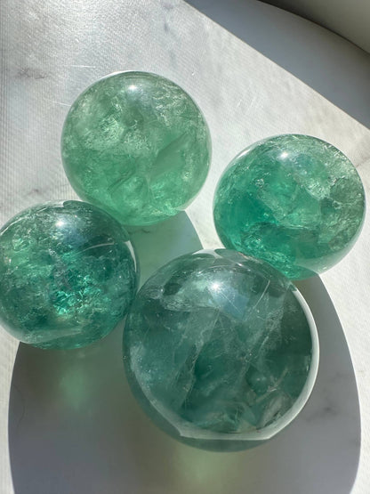 Natural Green Fluorite Sphere set of four with sparkling translucent surfaces and unique swirling patterns